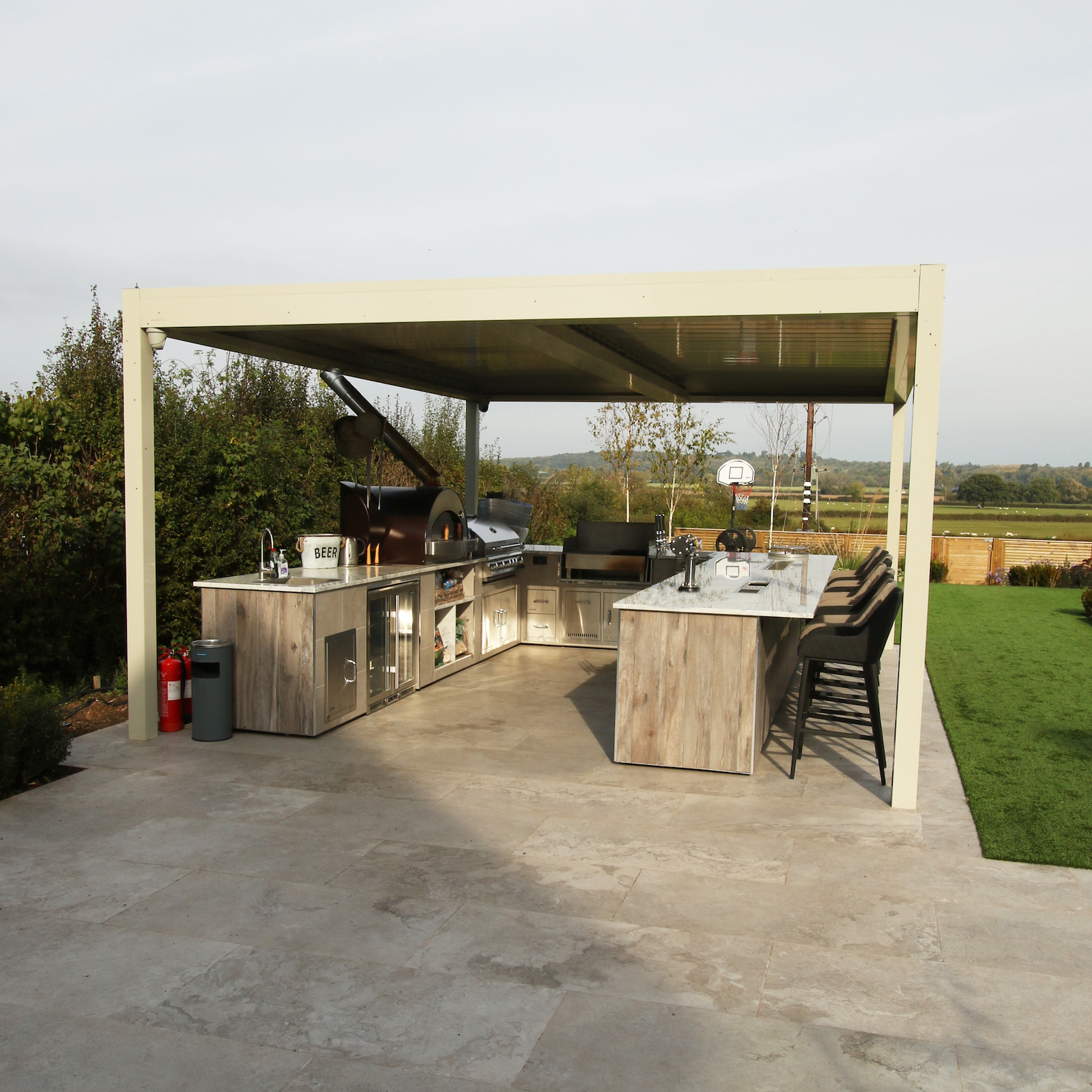 Bespoke outdoor kitchen with pizza oven, gas BBQ, charcoal BBQ, fridges _ sink